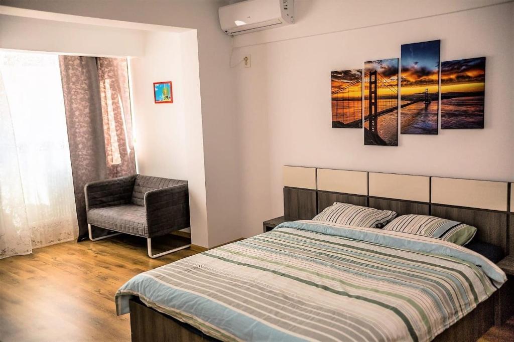 een slaapkamer met een bed en een stoel bij Apartament Ira Mamaia Nord in Mamaia Nord – Năvodari