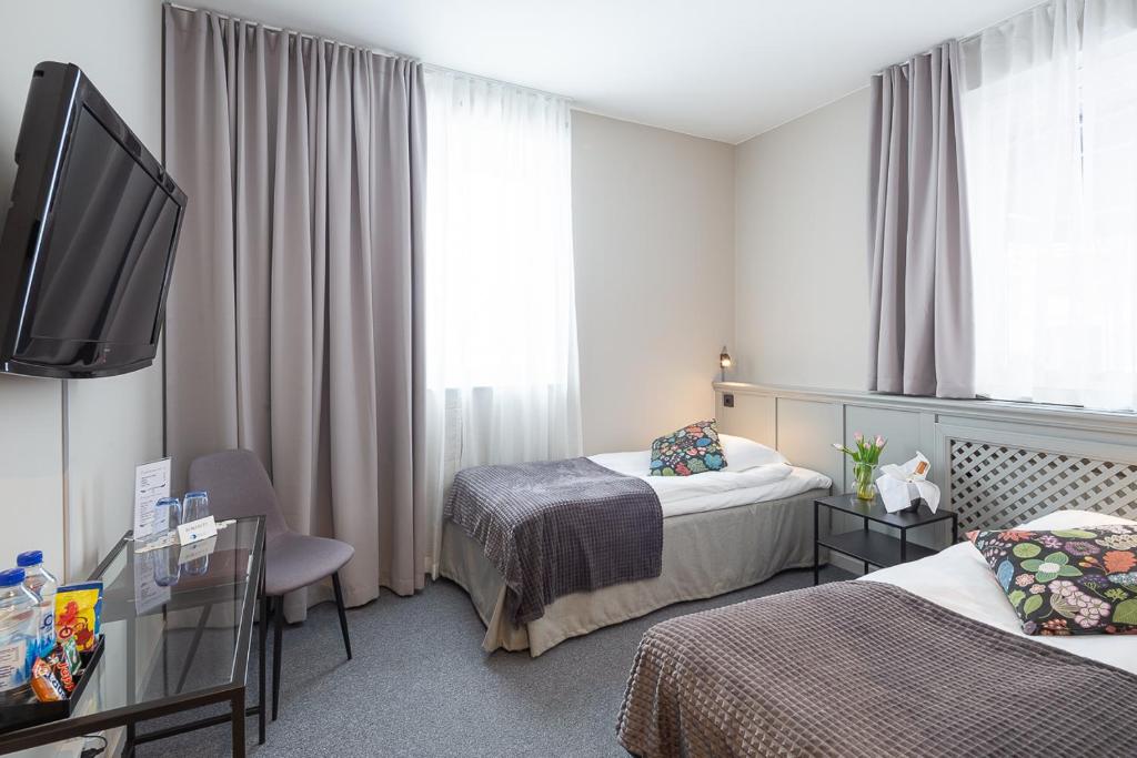 a hotel room with two beds and a flat screen tv at Hotell Leksand in Leksand