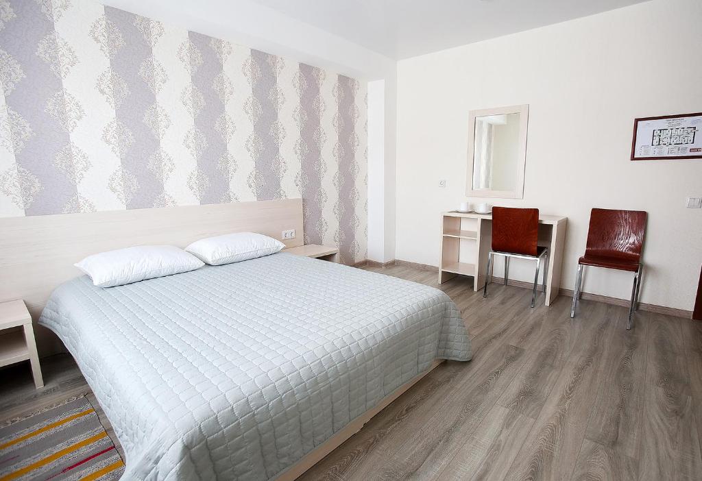 1 dormitorio con 1 cama, escritorio y sillas en Гостиница Старый Город, en Barnaul
