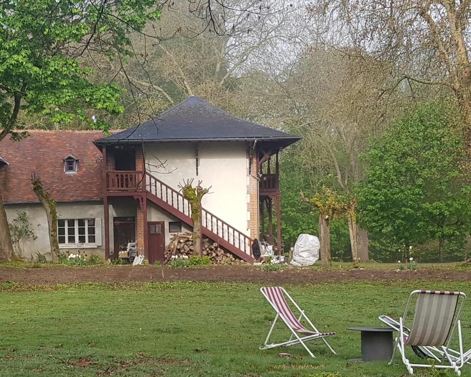 una casa con terraza y 2 sillas en el patio en Gîte dans le parc d'une maison ancienne près des bords de Loire en Ouzouer-sur-Trézée