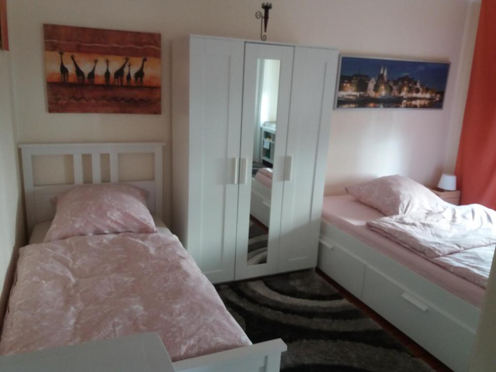 1 dormitorio con 2 camas y espejo en Pensionszimmer Lützowzimmer, en Lübeck