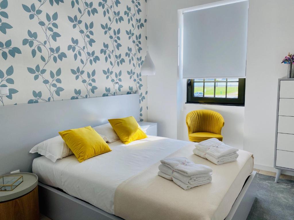 Un dormitorio con una cama con almohadas amarillas y una silla amarilla. en Family Hostel Costa Nova en Costa Nova