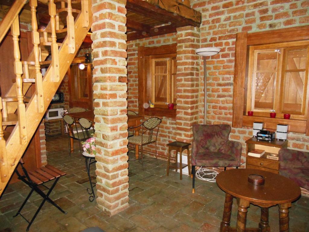 a room with chairs and tables and a brick wall at Cottage Plavi Lav Potok in Potok