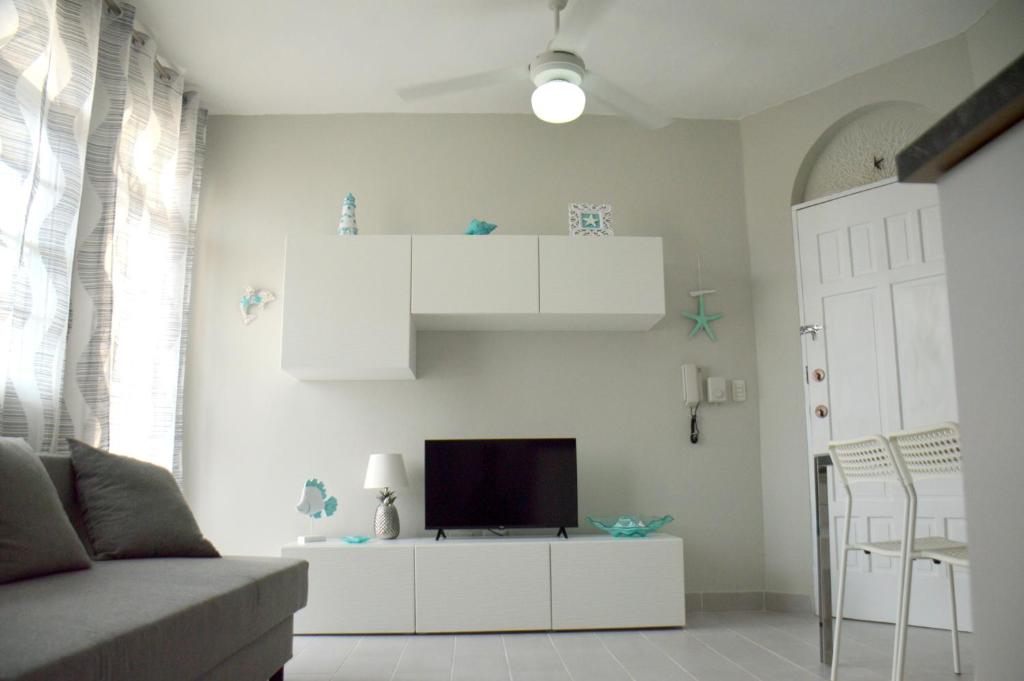 - un salon avec une télévision sur un meuble blanc dans l'établissement Caribe Apartament S&D el castillo dominicus Apartamento #9, à Bayahibe