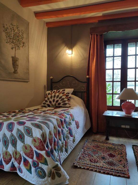 a bedroom with a bed and a table and windows at La Commanderie in Loison-sur-Créquoise