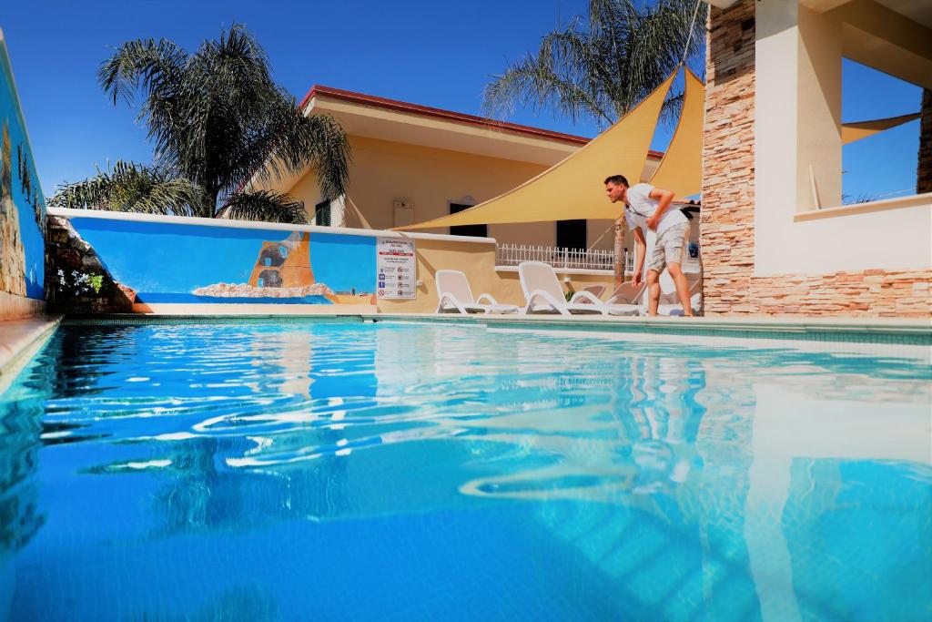 a man and a woman standing next to a swimming pool at Villa Paglianiti - Your FAMILY Residence! in Briatico