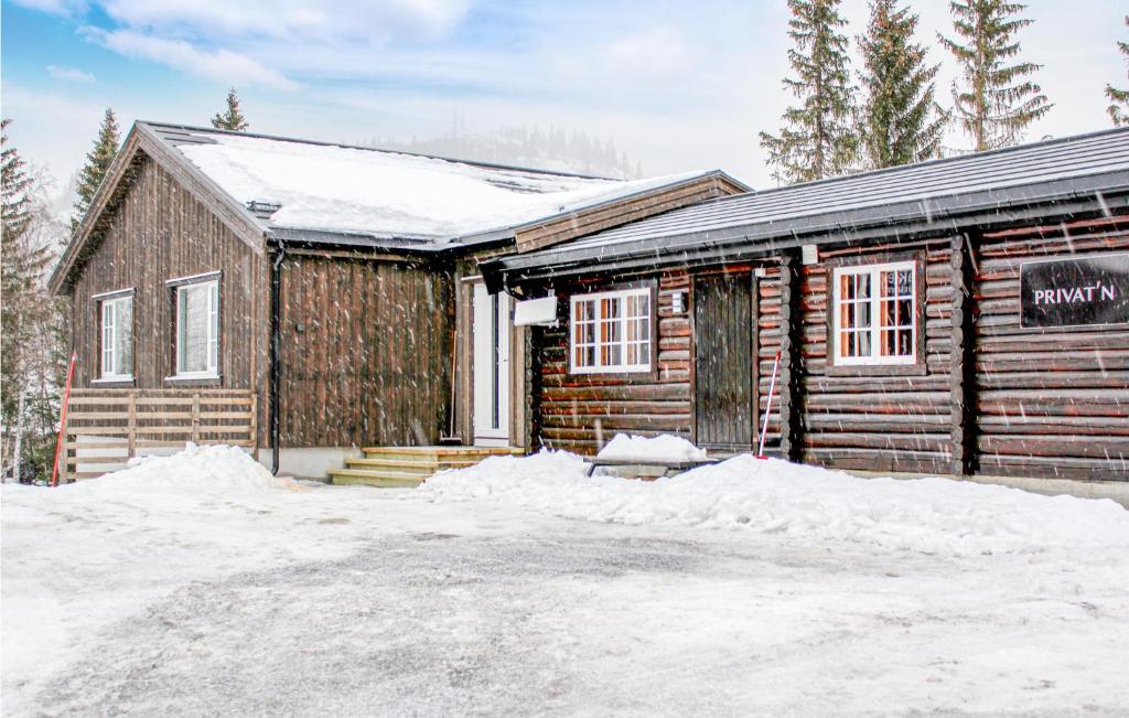 une cabane en rondins avec de la neige devant elle dans l'établissement Privatn, à Hemsedal