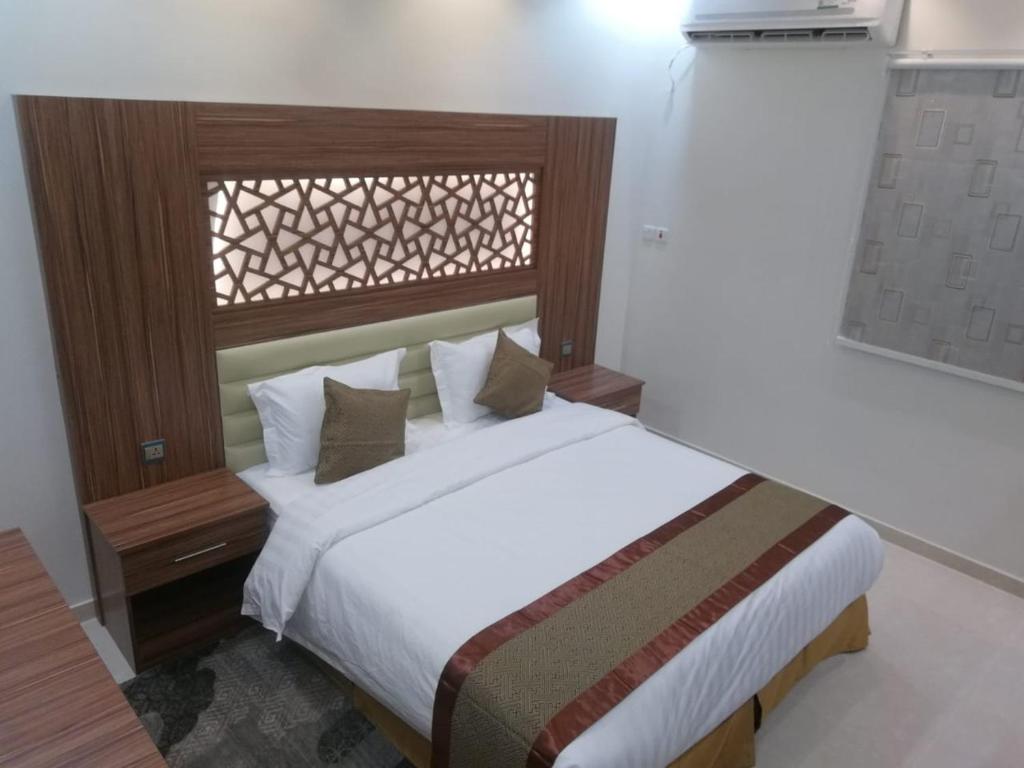 1 dormitorio con 1 cama grande y cabecero de madera en روز للوحدات السكنيه, en Al Thybiyah