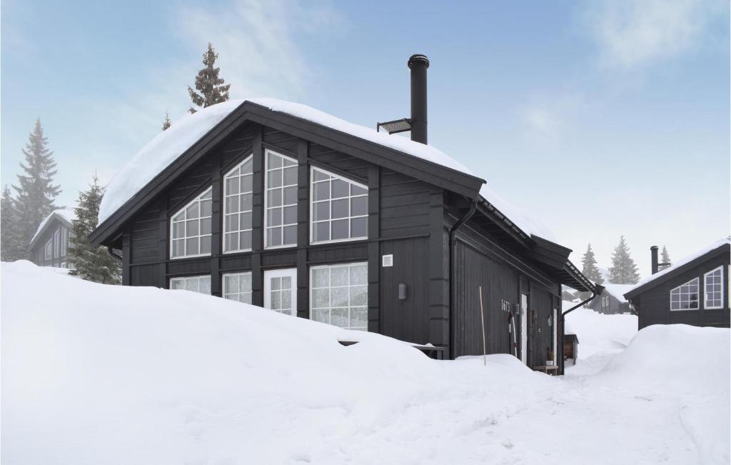 un bâtiment recouvert de neige avec un tas de neige dans l'établissement Gorgeous Home In Sjusjen With House A Mountain View, à Sjusjøen