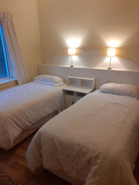 2 camas num quarto com 2 candeeiros na parede em Joan B+B em Clonakilty