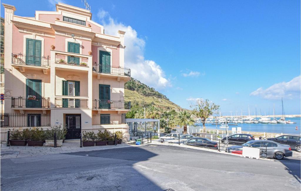 a pink building with cars parked next to a marina at Cozy Apartment In Castellammare Dg in Castellammare del Golfo