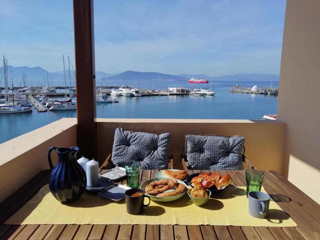 a table with food on a balcony with a view of a harbor at Aegina Port Apt 2-Διαμέρισμα στο λιμάνι της Αίγινας 2 in Aegina Town