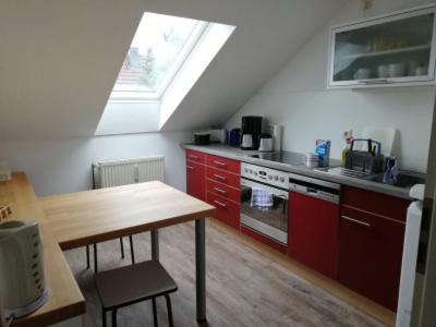 cocina con armarios rojos, mesa y ventana en FeWo Dannies, en Altdöbern