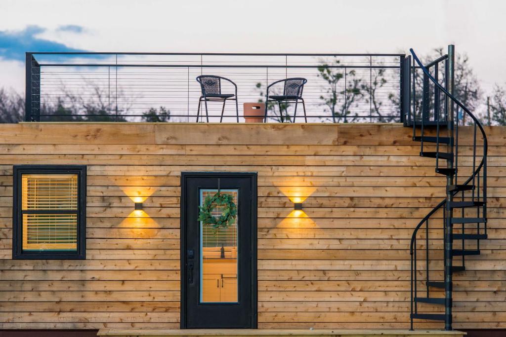 a house with a balcony with two chairs on top of it at The Meadows Shipping Container Home in Bellmead