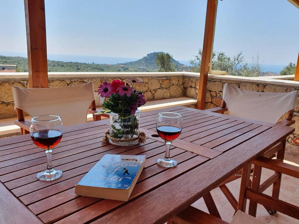 a wooden table with two glasses of wine and a book at Stoupa Lefktro 10 in Levktron