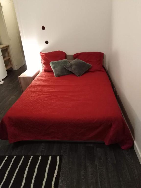 - un lit rouge avec deux oreillers dans l'établissement Appartement pres de beauval et des châteaux, à Montrichard