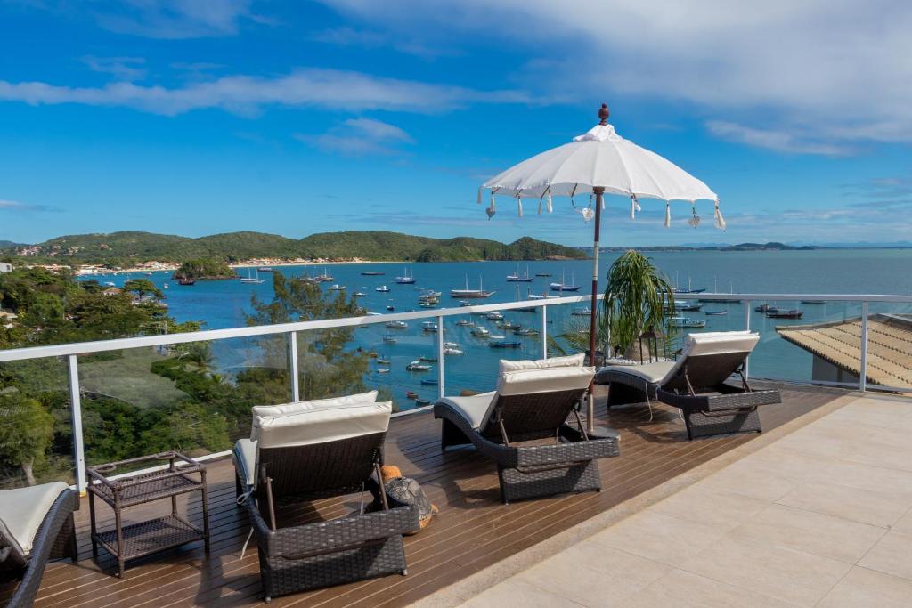 a deck with chairs and an umbrella and the water at Pousada Ao Por do Sol in Búzios