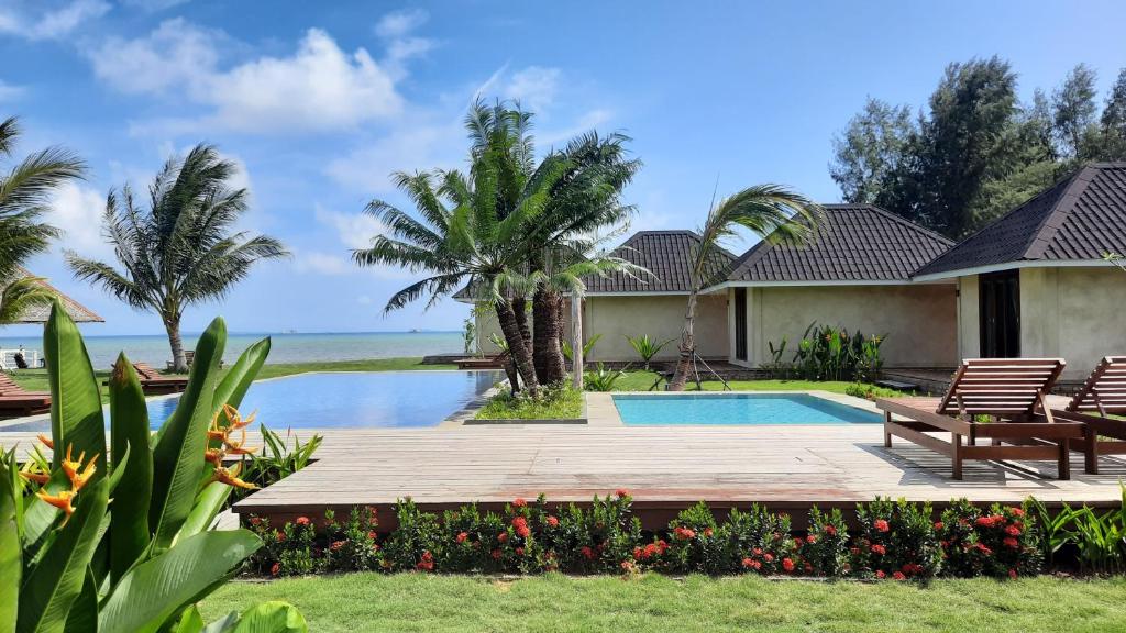 una villa con piscina e palme di The Kelong Trikora Resort a Kangkakawal