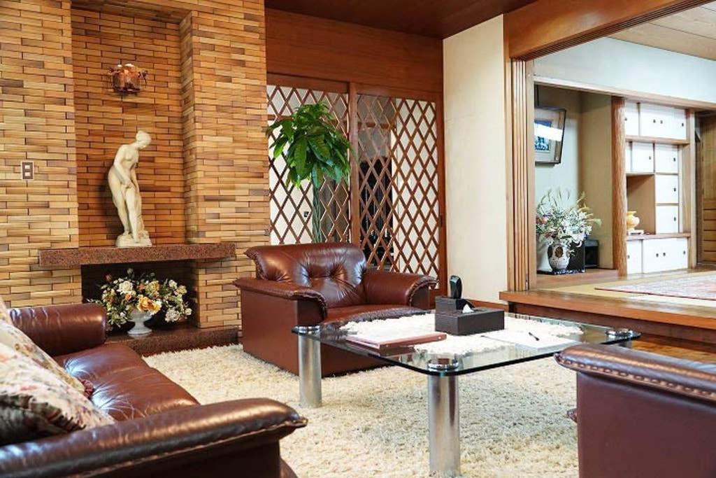 a living room with leather couches and a table at THE TORII in Kumamoto