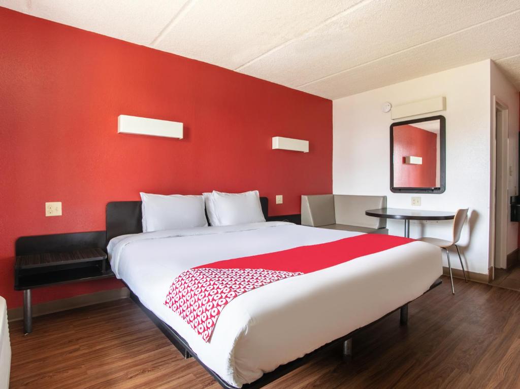 1 dormitorio con 1 cama grande y pared roja en OYO Hotel Lake Park/Valdosta I-75 en Lake Park