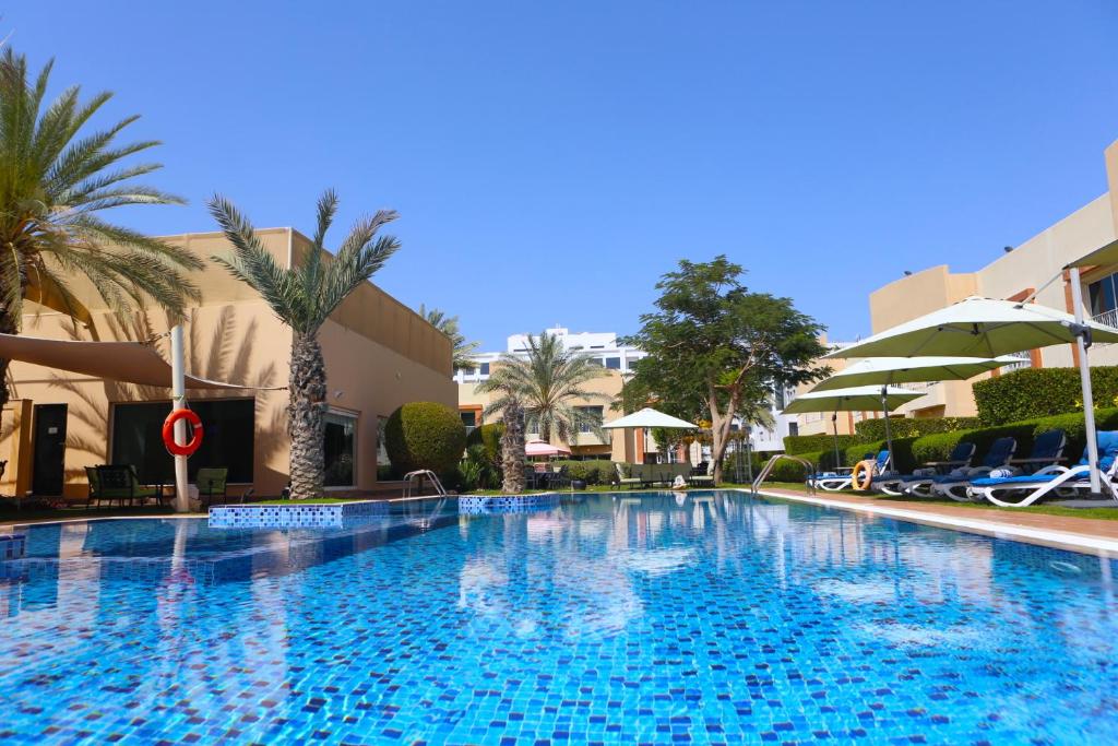 a large swimming pool in a hotel with palm trees at Coral Boutique Villas in Dubai