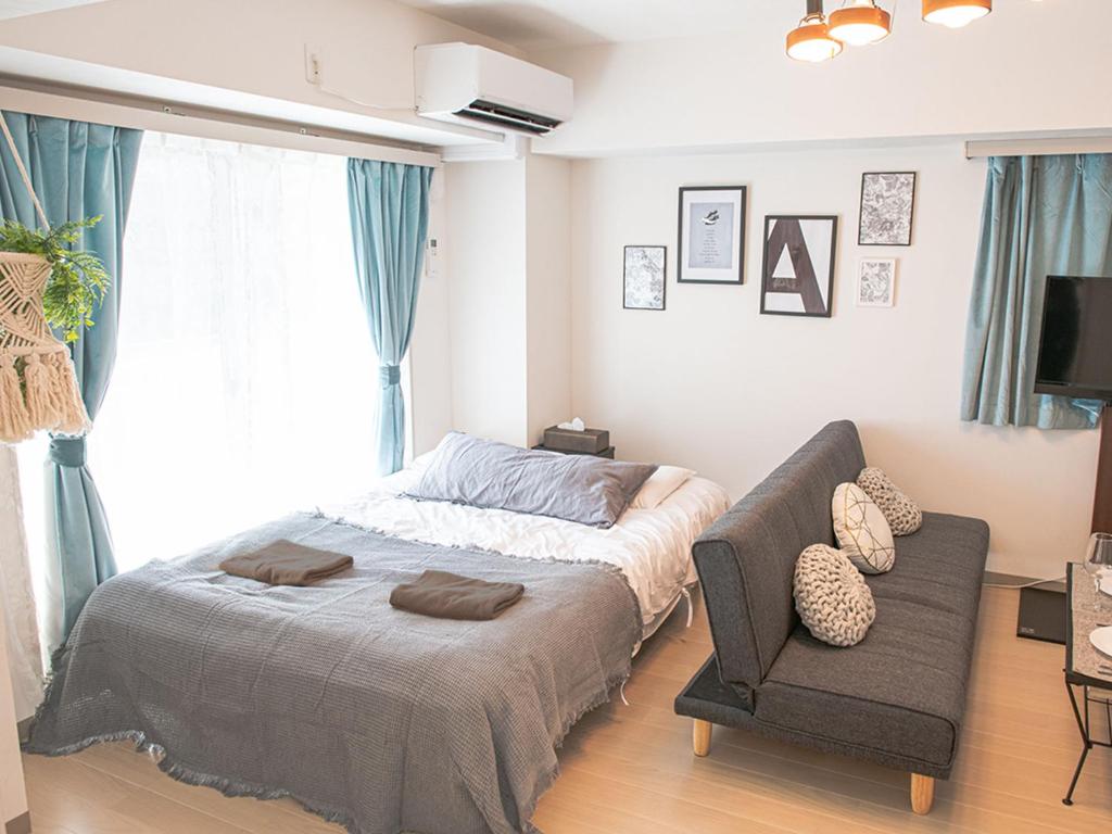 ein Schlafzimmer mit einem Bett und einem Sofa in der Unterkunft LY INN Ryogoku Annex in Tokio
