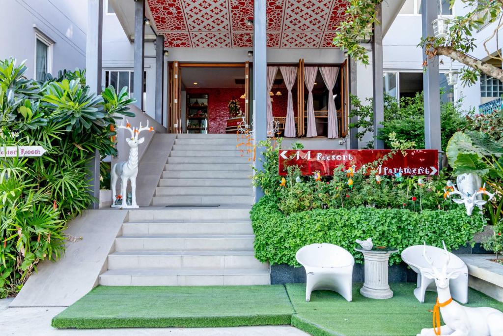 a building with stairs and plants and white chairs at AA Resort Hotel in Pak Kret