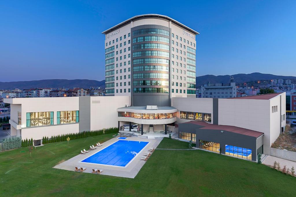 a large building with a swimming pool in front of it at Dedeman Tokat in Tokat