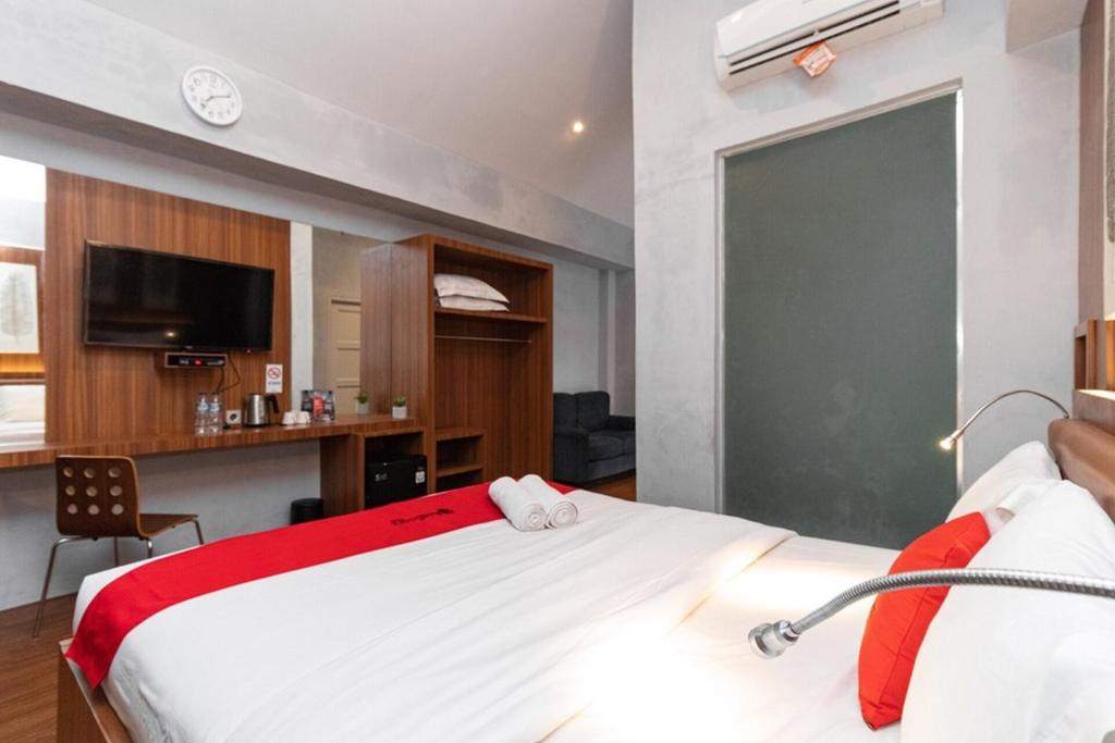 a bedroom with a large white bed with a red blanket at RedDoorz Premium near Centre Point Mall Medan in Medan
