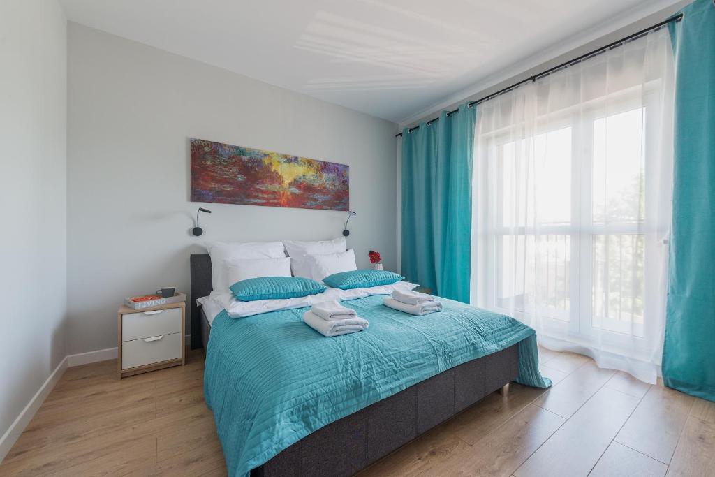 una camera da letto con un letto con lenzuola blu e una finestra di Airport Bakalarska P&O Serviced Apartments a Varsavia