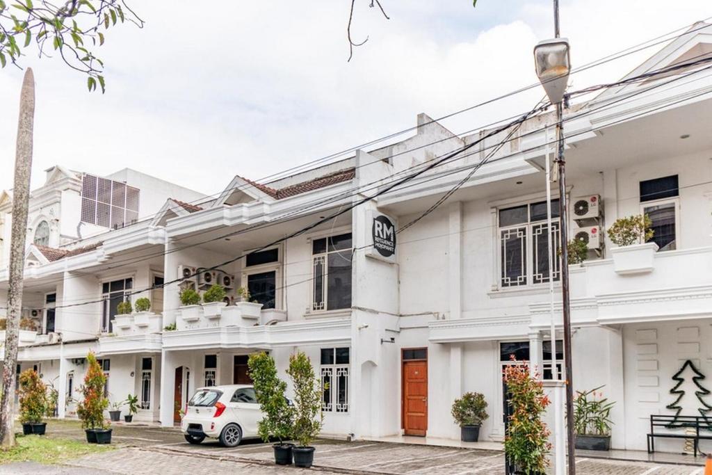 a white building with a car parked in front of it at RedDoorz @ Jalan Mojopahit Medan in Medan