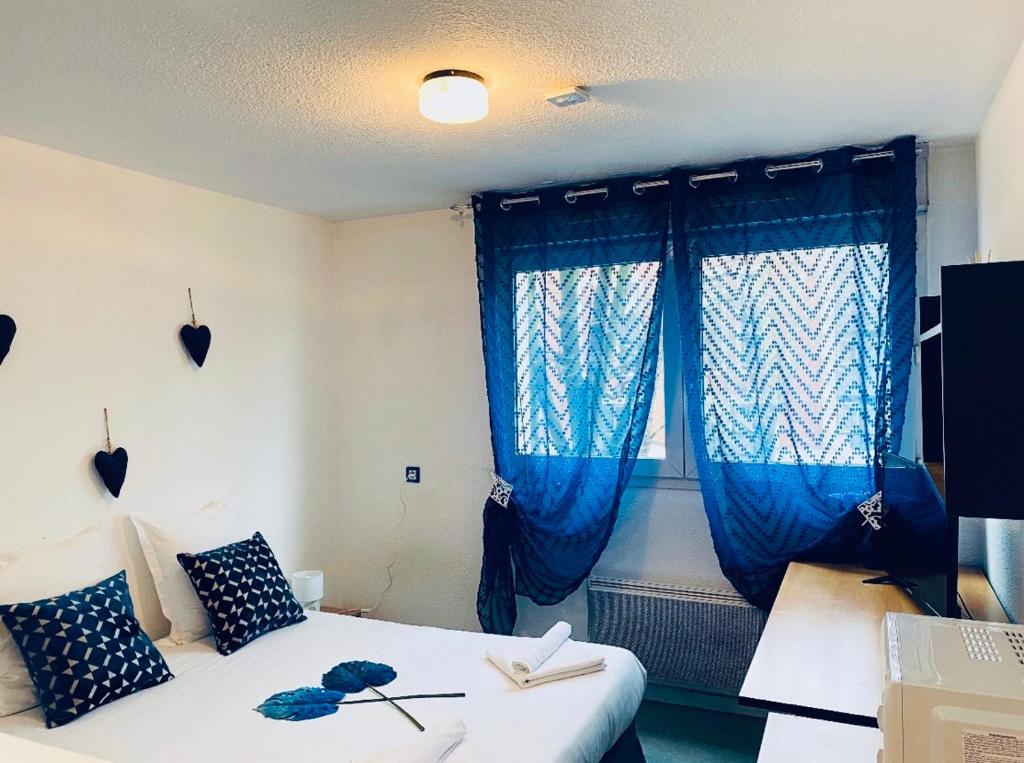 um quarto com uma cama com cortinas azuis e uma janela em Neoresid - Résidence Saint Marc em Rouen