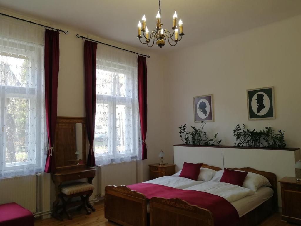 a bedroom with a bed with red curtains and a chandelier at TulipánVendégház in Keszthely