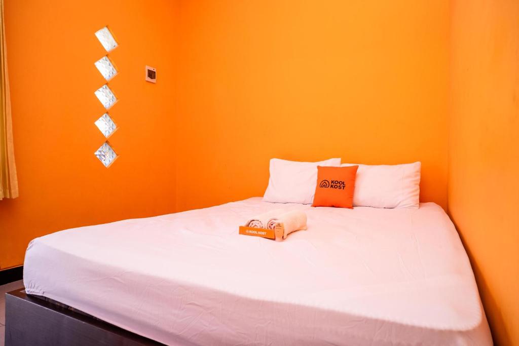 a bedroom with a bed with an orange wall at Sitiinggil Syariah RedPartner in Tegal