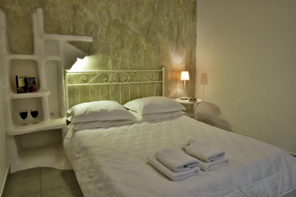 Un dormitorio con una cama blanca con toallas. en Adamas Hotel en Adamas