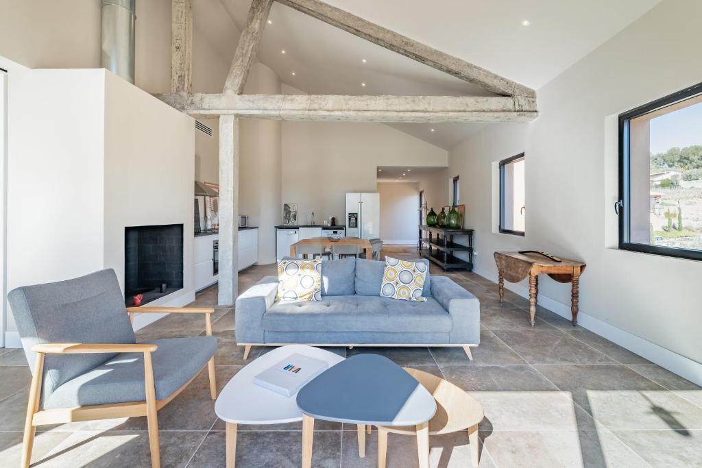 ein Wohnzimmer mit einem blauen Sofa und Stühlen in der Unterkunft Loft d'architecte au coeur d'un domaine viticole in La Cadière-dʼAzur