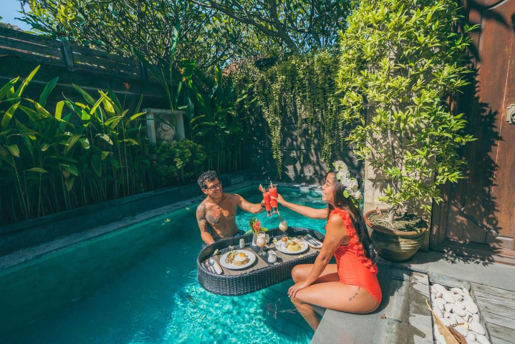 een man en vrouw aan een tafel in een zwembad bij Nyuh Bali Villas in Seminyak