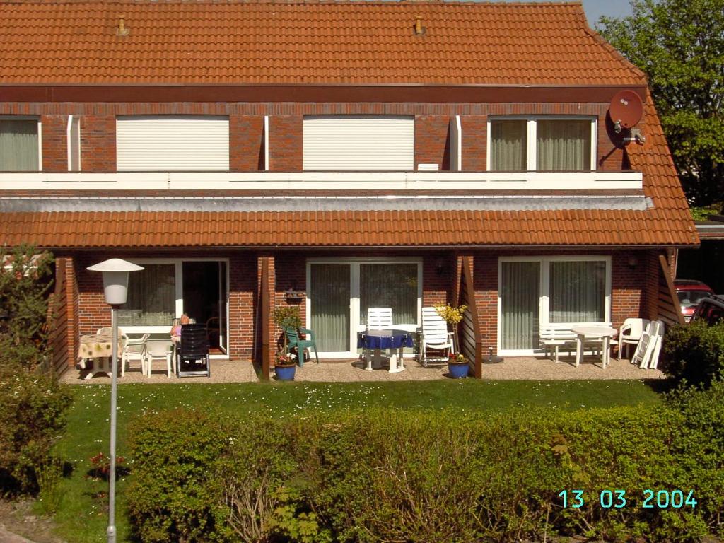 een stenen huis met een patio en tafels en stoelen bij Ferienwohnung Besslich Wattweg 5 in Norden