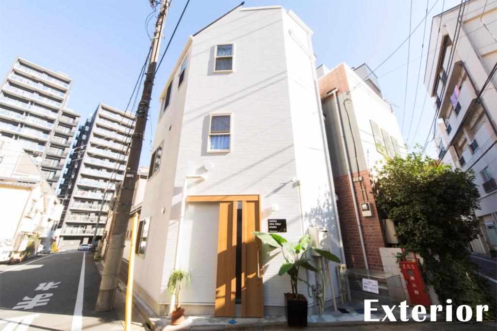 a white building on a street with tall buildings at nestay villa tokyo otsuka in Tokyo
