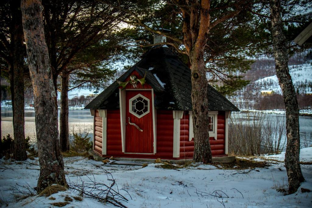 a red cabin with a red door in the snow at Tysfjord Hotel in Storjord I Tysfjord