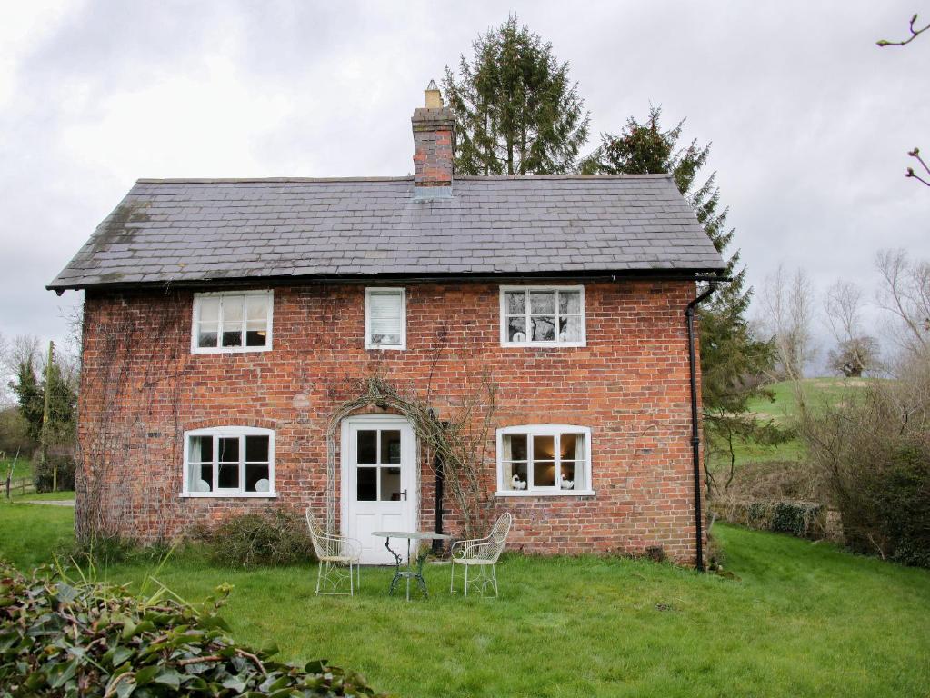 a brick house with a table and chairs in the yard at Wolvesacre Mill Cottage in Whitchurch