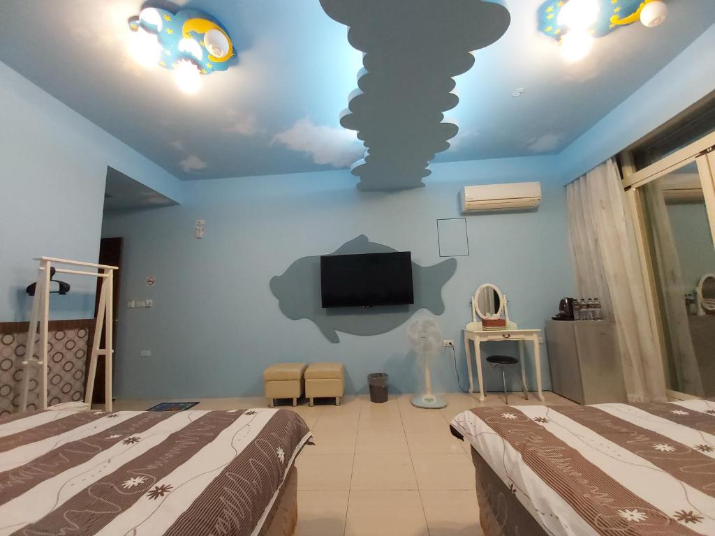 a bedroom with two beds and a flat screen tv at Happy Heart B&amp;B in Taitung City