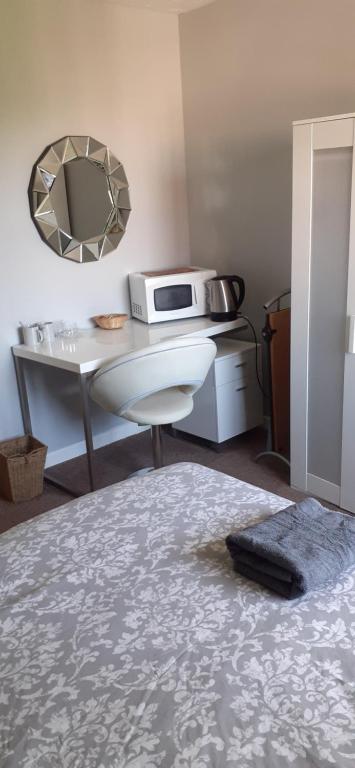 a room with a bed and a table with a microwave at Constantine Court Homestay in Shepton Mallet