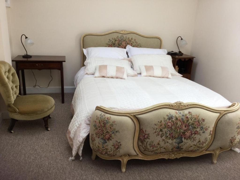 a bedroom with a large bed and a chair at wingate cottage in Southburgh