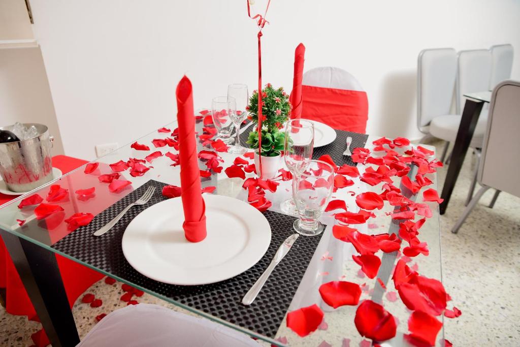 a table with red flowers and red candles on it at Hotel Arawak Upar in Valledupar