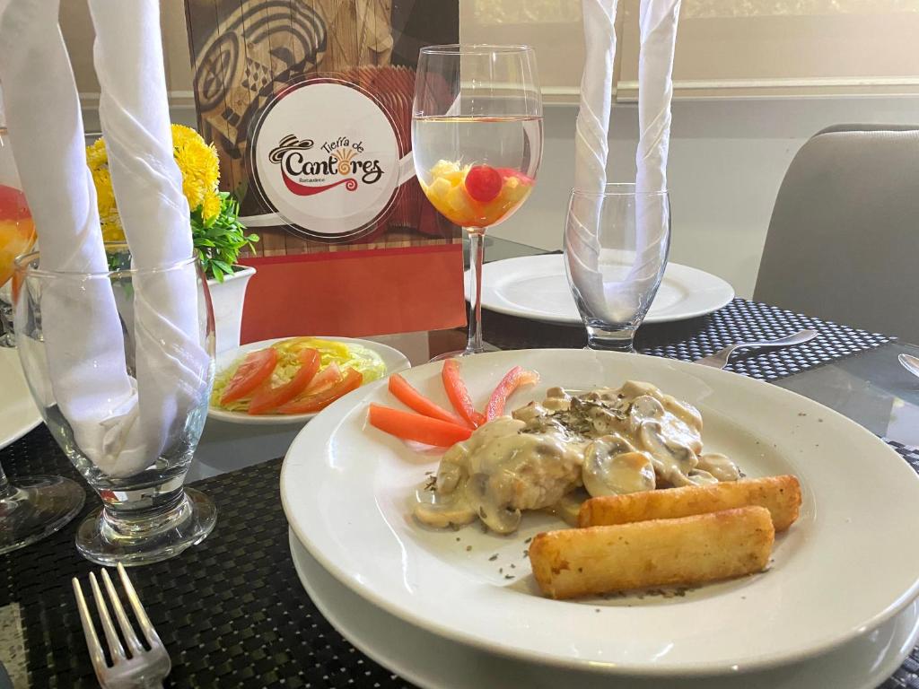 a plate of food on a table with wine glasses at Hotel Arawak Upar in Valledupar