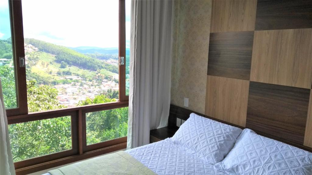 um quarto com uma cama e uma grande janela em Apto Residencial Vista Azul - Pedra Azul - ES em Domingos Martins