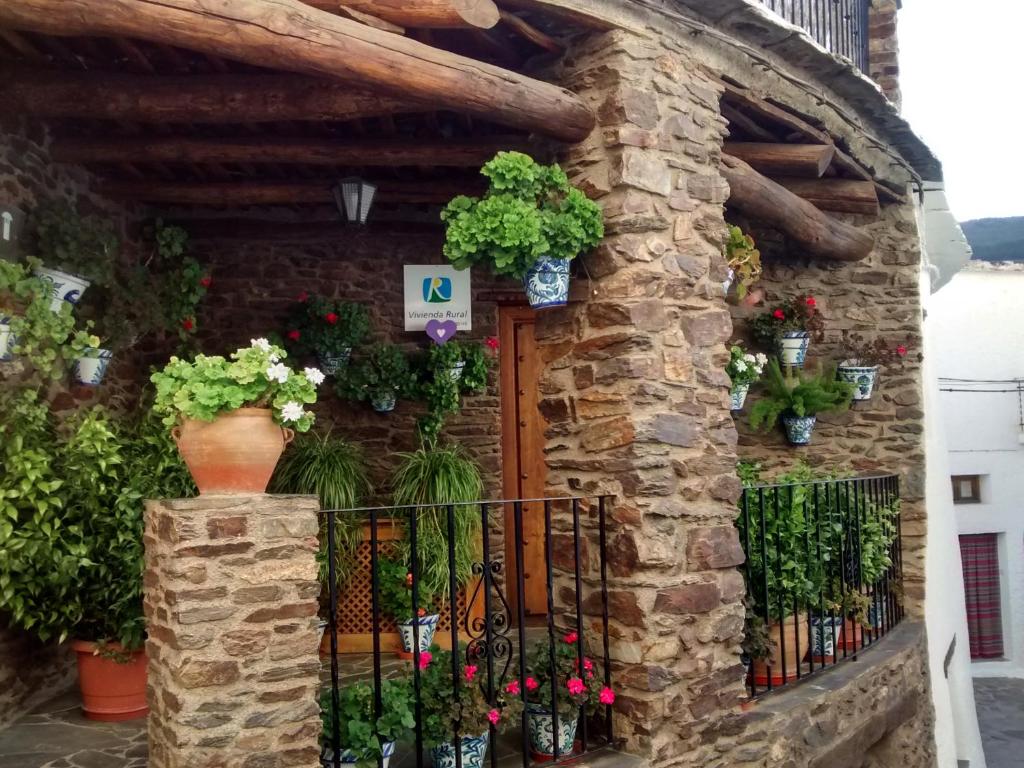 a stone building with a gate with flowers and plants at Casa Fina in Bubión