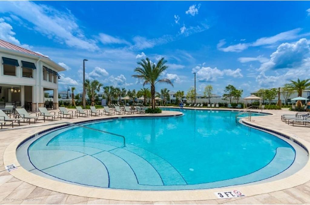 una piscina en un complejo con sillas y palmeras en Four-Bedroom Townhome Kissimmee, en Orlando