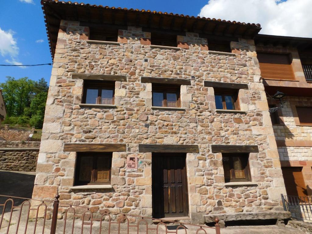 un antiguo edificio de piedra con 6 ventanas en Las Hoyas I y II, en Tolbaños de Arriba